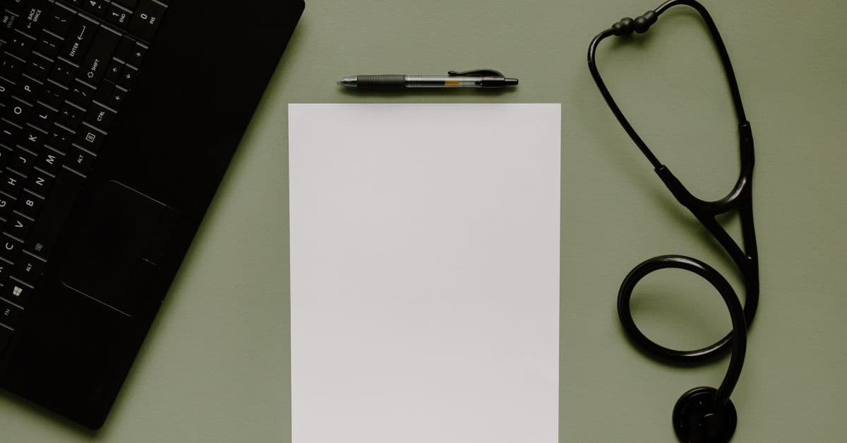 A stethoscope and laptop on a medical coding desk